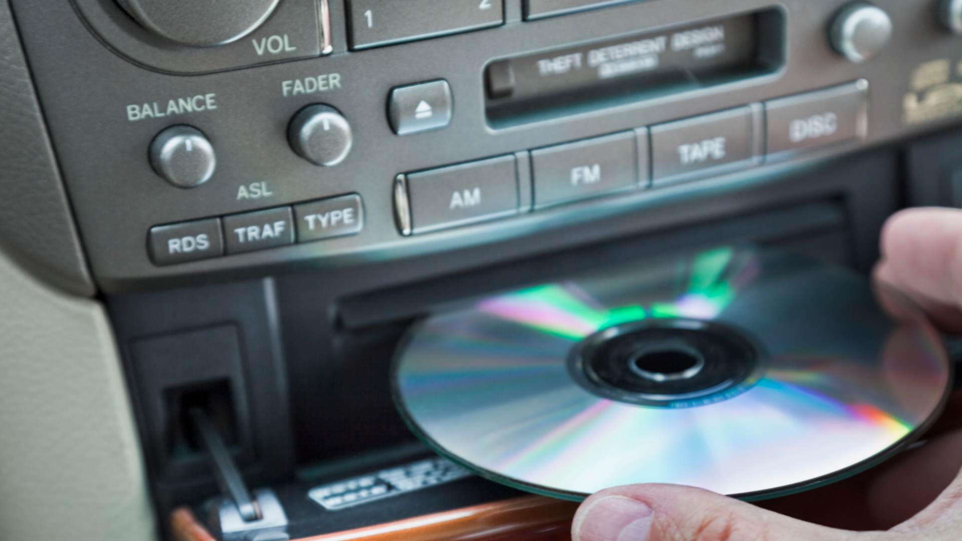 A person inserting a CD into car CD player